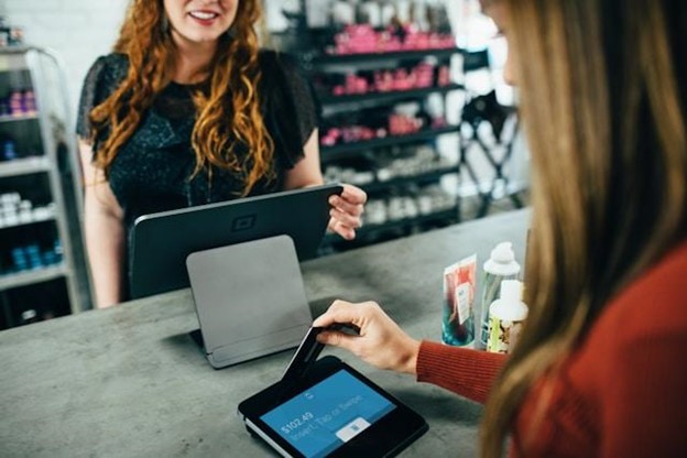 Consistent quality creates a loyal customer base and encourages repeat business. Alt text: Woman in a red shirt using her credit card in a store